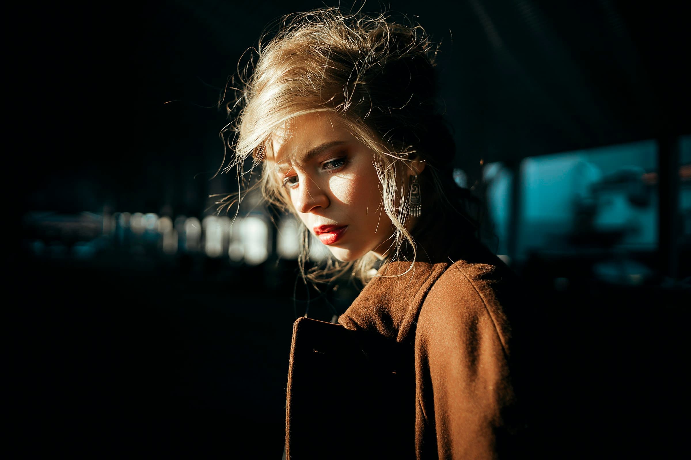 Model in an espresso wool coat seated on a stone plinth in raking autumn light