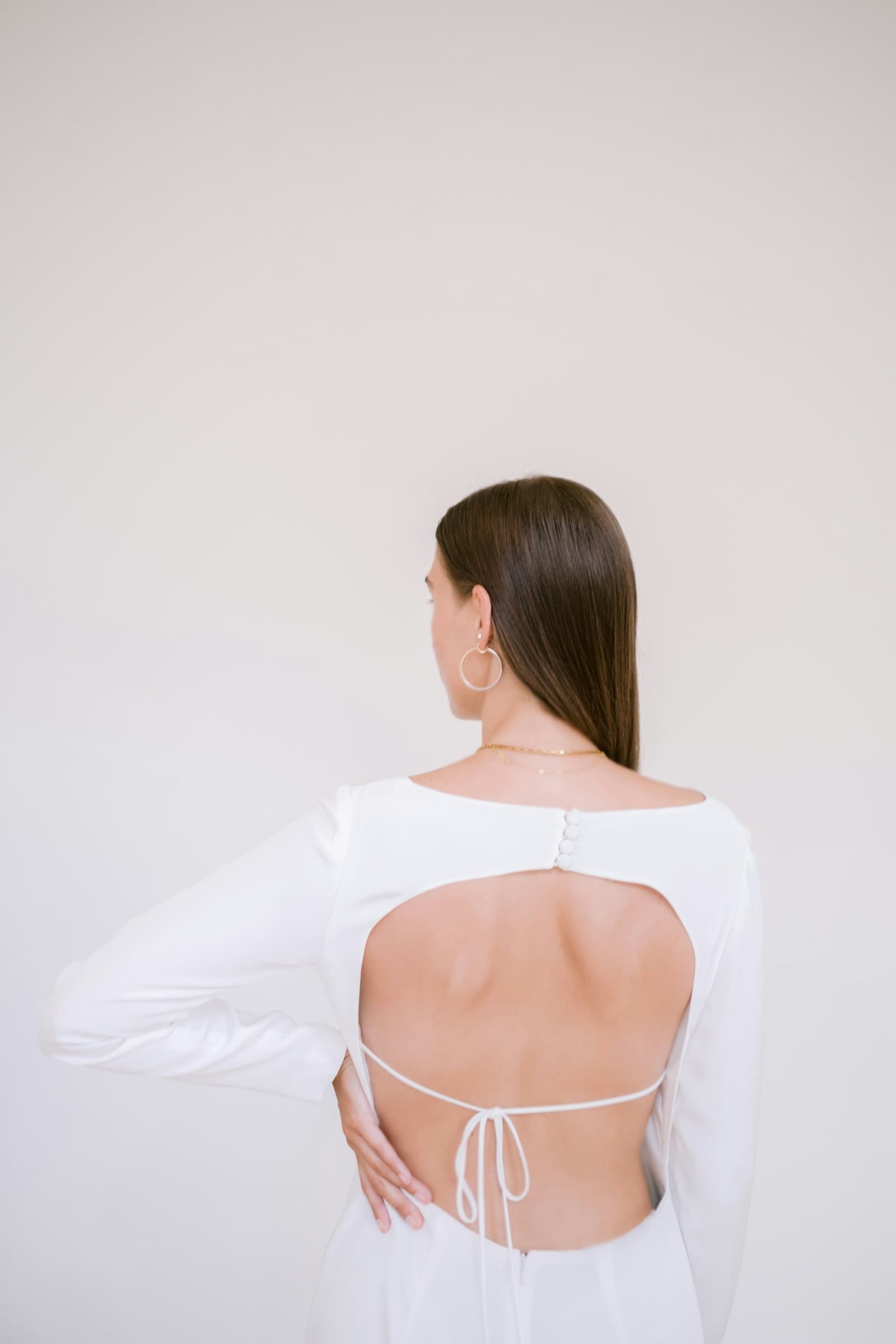 Model with an ivory drape falling from her shoulders, seen from behind