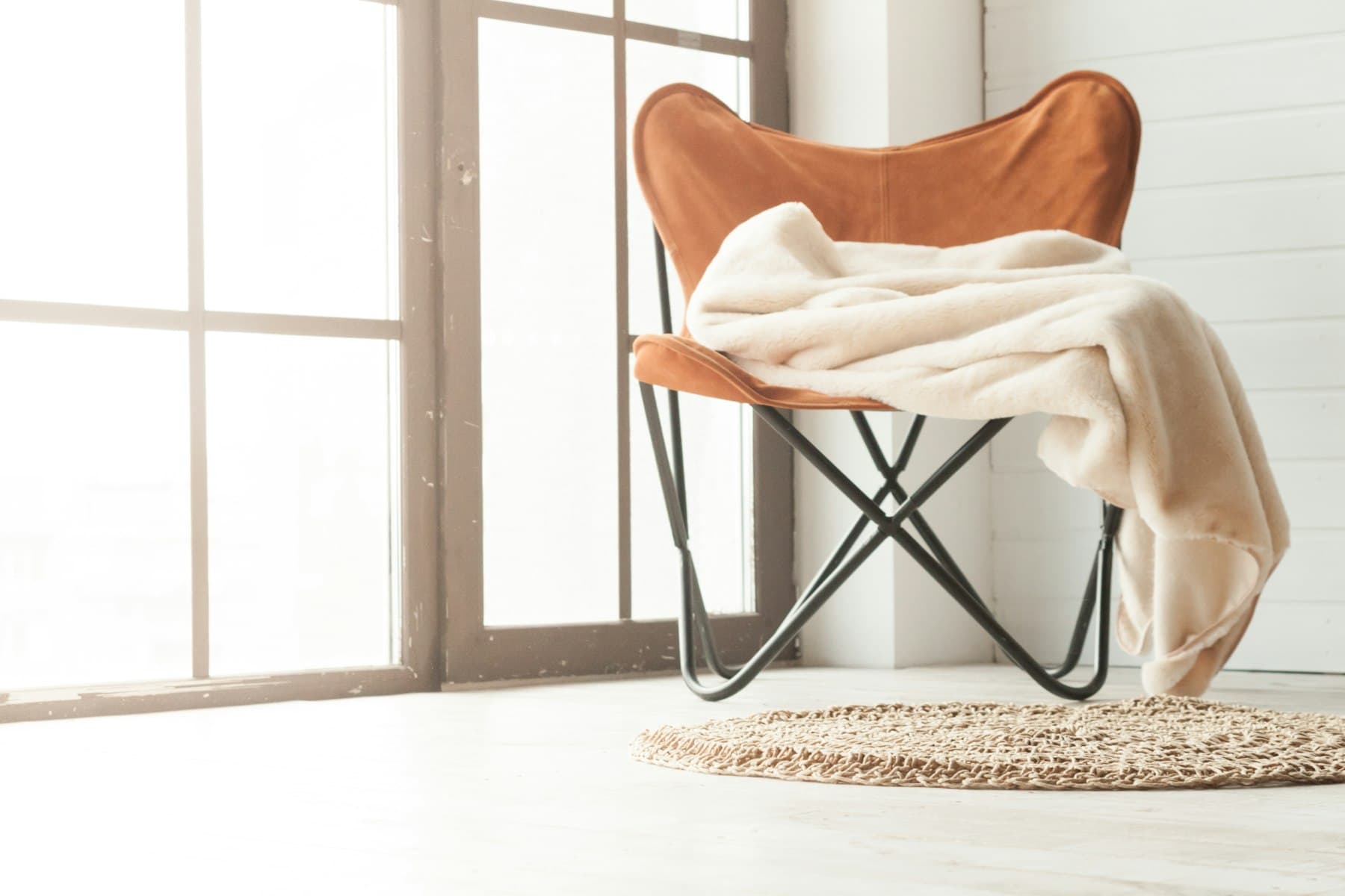 An ivory throw draped over a wooden chair in warm light