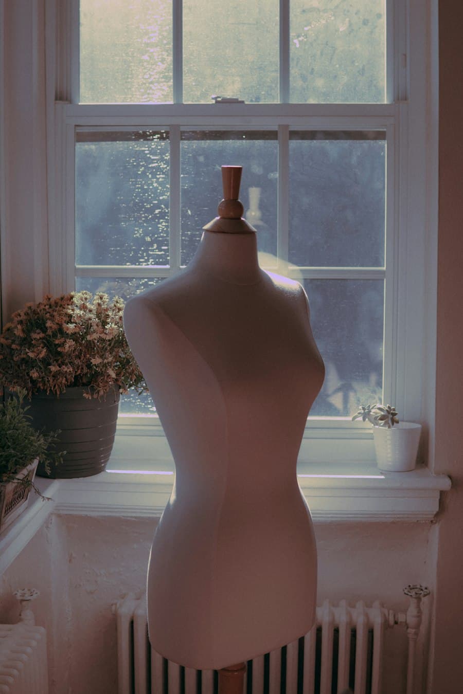 A dress form and pinned sketches in a sunlit studio