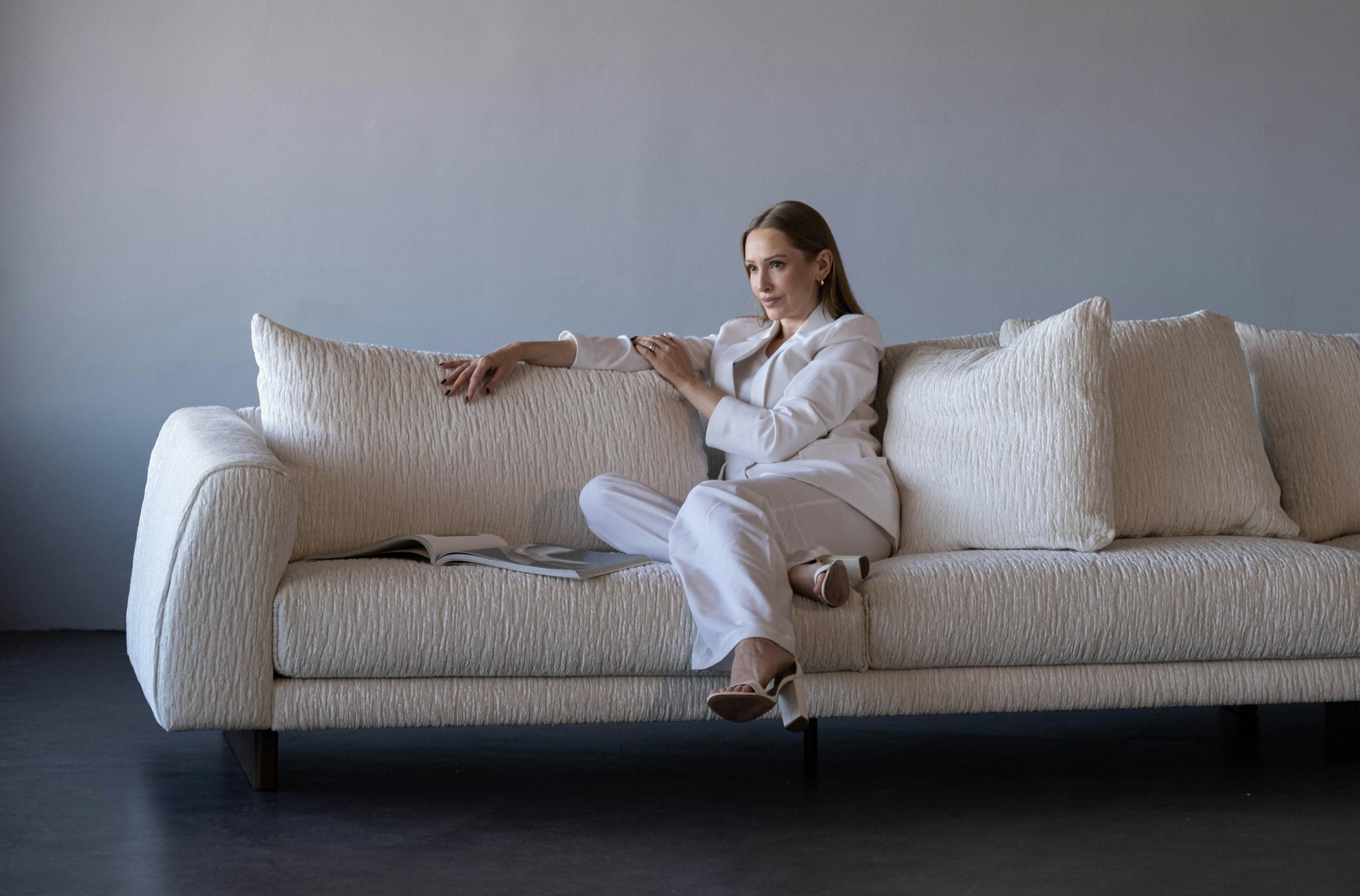 Model in an ivory suit and scarf seated on stone steps